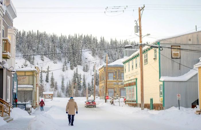 A pedestrian strolls down Queen St toward the Klondike Hwy and the Yukon River on a bitterly cold winter evening in Dawson City, Yukon.