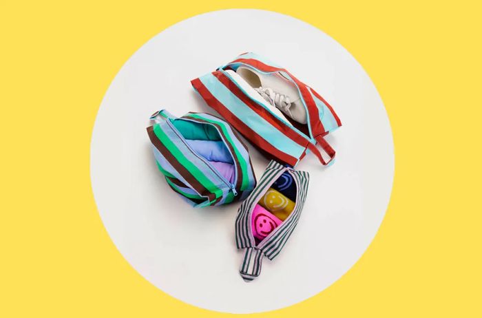 Set of three striped Baggu 3D Zip pouches filled with clothing and shoes