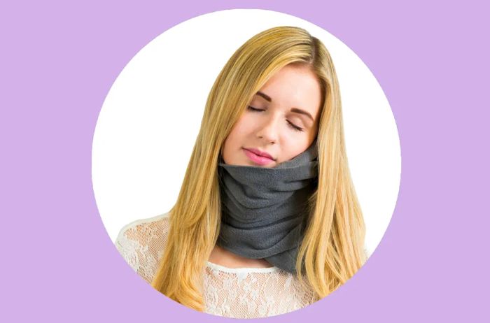 Woman wearing a gray Trtl travel pillow around her neck