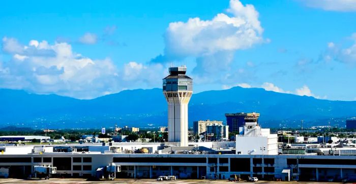 Air traffic control tower situated against a backdrop of hills and clouds