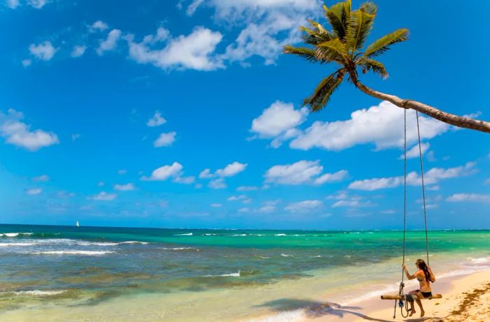 A woman relaxing on a beach swing hanging from a palm tree on Little Corn Island