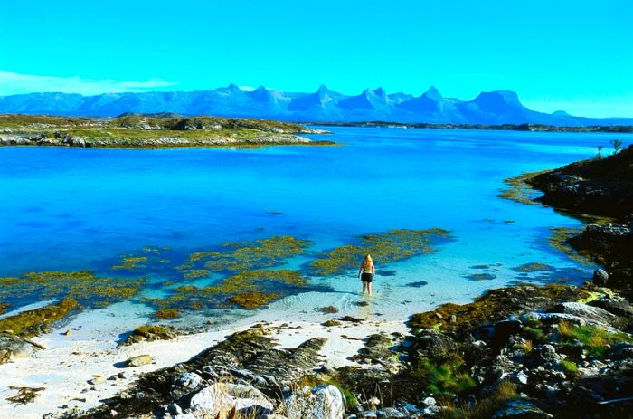 A child playing in the colorful waters and sandy shores of Helgeland in northern Norway