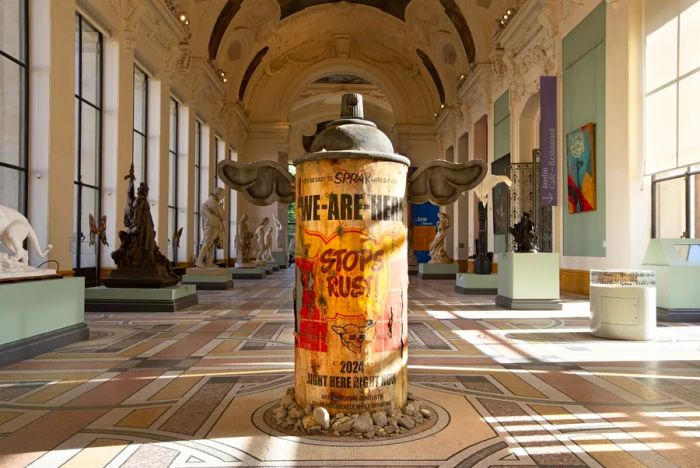 Sculpture of a winged spray can displayed inside the gallery