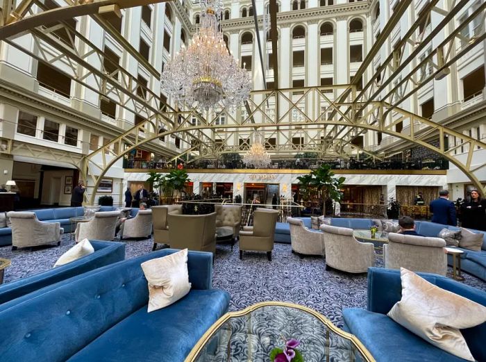 The courtyard lobby of the Waldorf Astoria Washington D.C., housed in a former post office, features blue and gray seating arrangements.