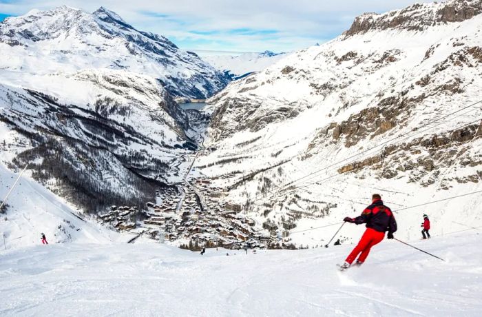 Two skiers dressed in red glide down the slopes high above the village of Val d'Isère.