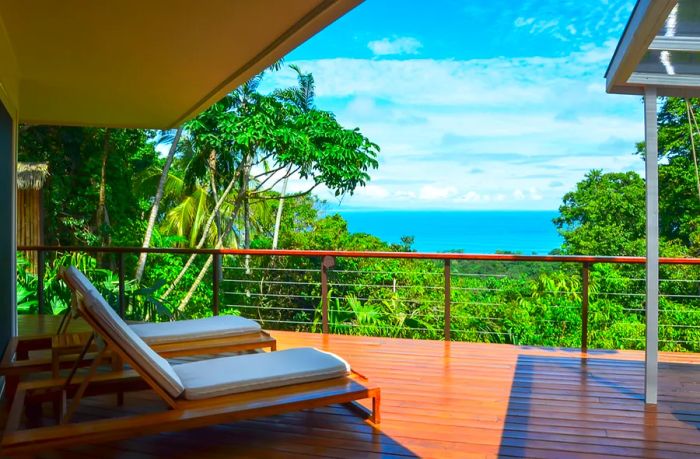 A stunning view of the ocean and rainforest from the wooden deck of the treetop Matapalo Suite at Lapa Rios Lodge in Costa Rica.