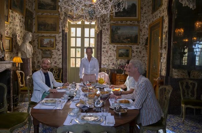 Quentin (Tom Hollander) and his entourage enjoy a meal at Villa Elena in 