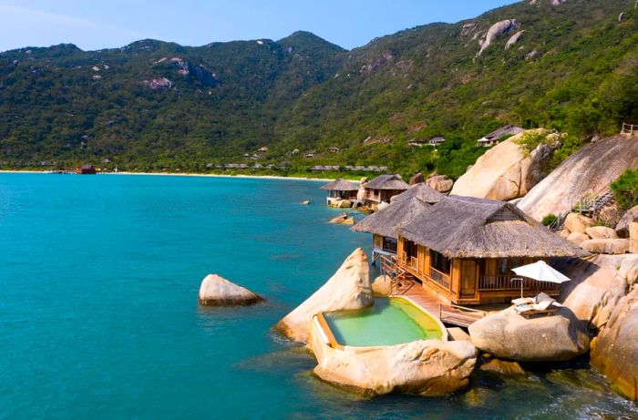 A Water Pool Villa at Six Senses Ninh Van Bay, perched on a rocky outcrop overlooking the ocean, features a private swimming pool adjacent to the water.