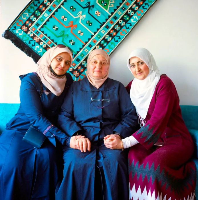 Lobna Helli (right), the chef and owner of Lazord, shares a moment with her mother, Noha (center), and her sister, Randa (left), underneath the restaurant’s iconic tapestry.