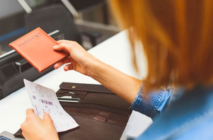 A person passing a passport with a protective cover to another individual.