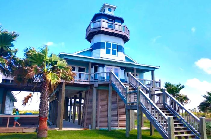 Charming striped lighthouse with a staircase leading to a wrap-around deck on the second floor