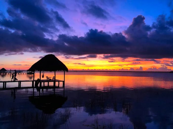 Pier by the water at sunset with a blend of purple and orange skies