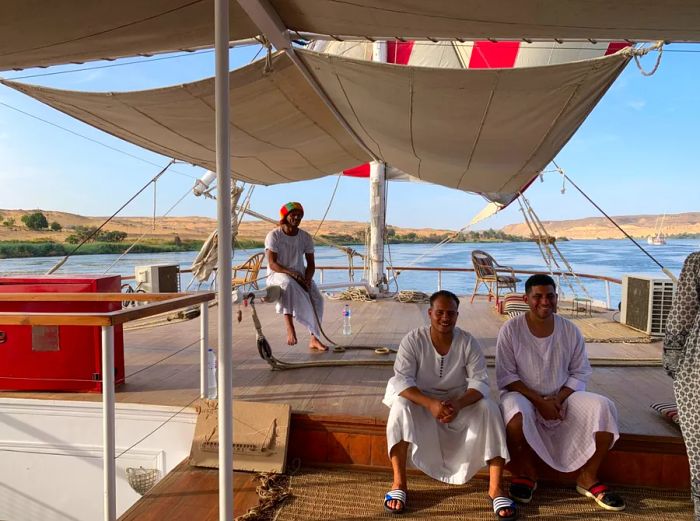 Crew members aboard a dahabiya sailboat relaxing on the deck