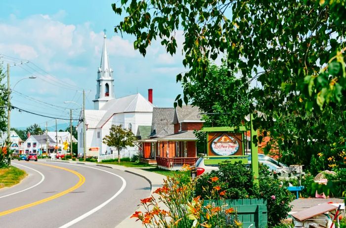 A winding road runs alongside a white church and house-like buildings.