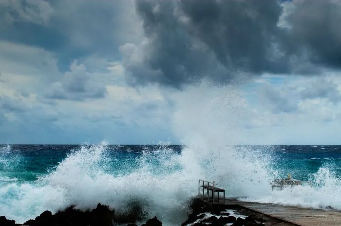 Hurricane Irma impacting the Grand Caymans: waves crashing against the shore beneath a dark, cloudy sky.