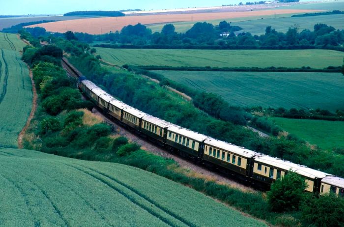 The vintage 1920s Belmond British Pullman glides through the lush fields of the English countryside.