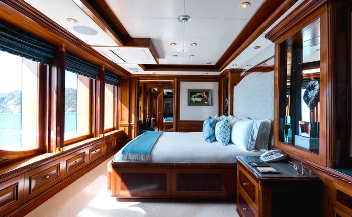 A bedroom aboard the Titania yacht featuring elegant wood paneling and a wall of windows