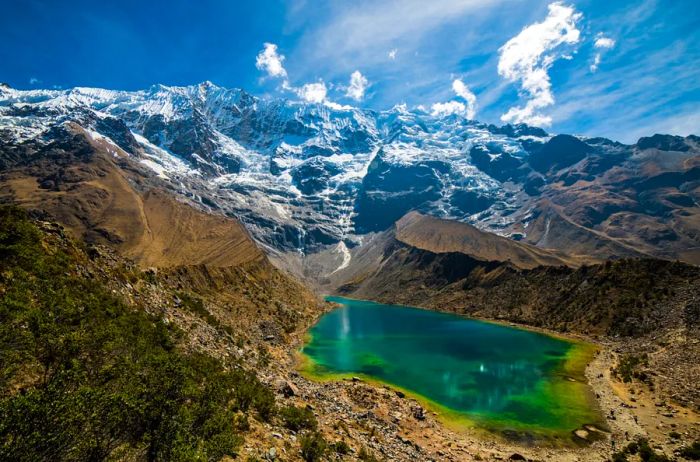 The stunning green-blue waters of Lake Humantay, framed by the snow-capped Andes, create a breathtaking sight in Peru.