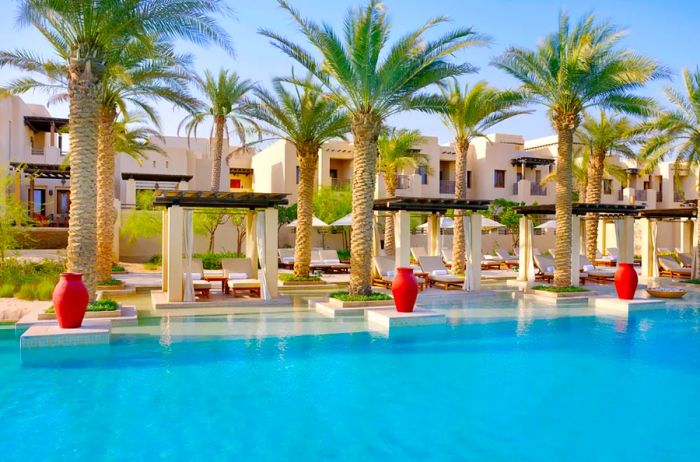 The pool at Al Wathba resort is bordered by lush palm trees.