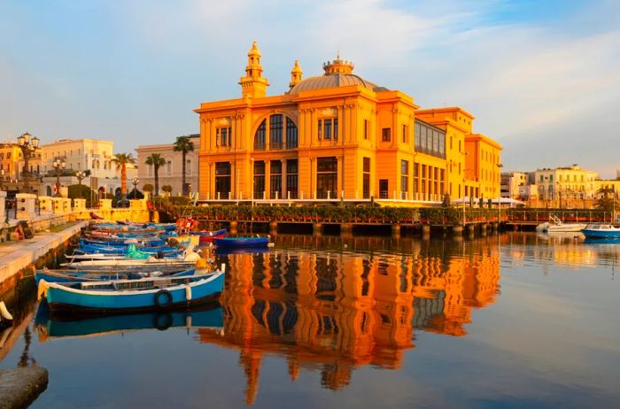 The dawn breaks over the harbor in Bari, Italy, highlighting the golden Teatro Margherita at the center