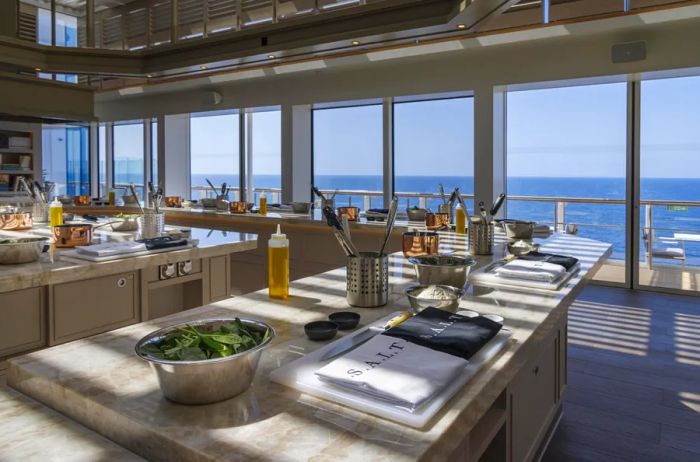 The S.A.L.T. Lab aboard the Silver Nova cruise ship features various cooking stations and expansive floor-to-ceiling windows that provide stunning sea views.