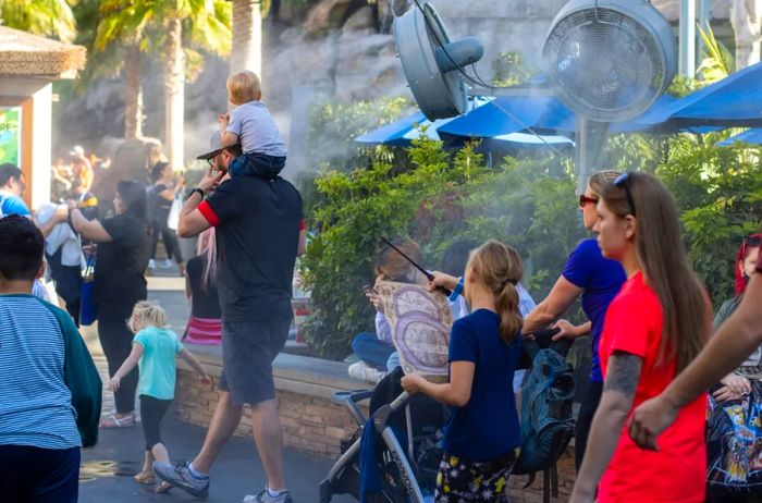 Adults and children walking in Universal City, California, enjoying misting fans.