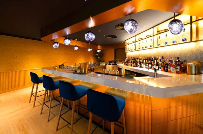 A bar featuring four unoccupied black high-top chairs can be found in the Chase Sapphire Lounge by the Club at Hong Kong.