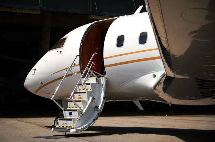 A sleek white private jet parked on the tarmac with its steps extended.