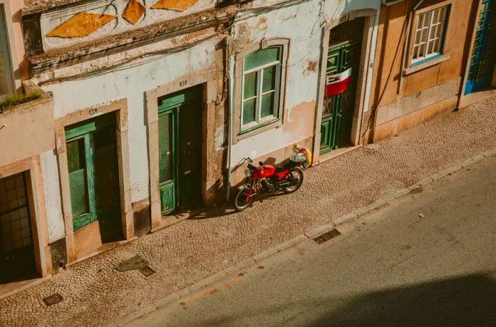 A glimpse of historical buildings and a vibrant red motorcycle on the streets of Faro, Portugal