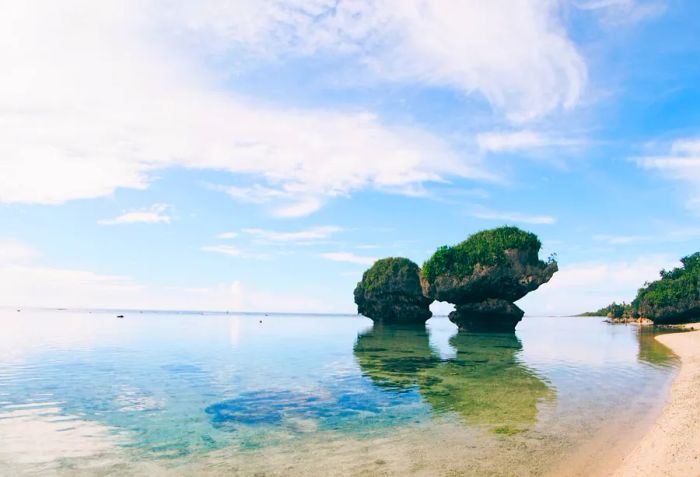 Tanguisson Beach in Guam, featuring two distinctive rock formations rising just off the shore