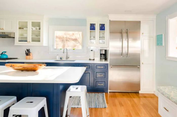 A contemporary kitchen featuring white bar stools surrounding a central island.