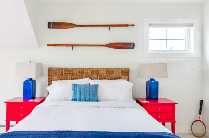 Bright bedroom featuring red and blue accents with two decorative oars above the bed