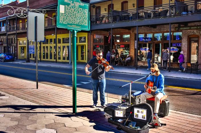 Guitarist and violinist performing on the sidewalk along Seventh Avenue