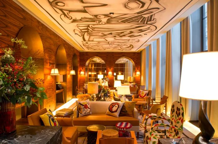 The reception area of the Brach Hotel in Paris features warm yellow lighting, numerous archways, and cozy sofas arranged around coffee tables, with a ceiling adorned in abstract art.