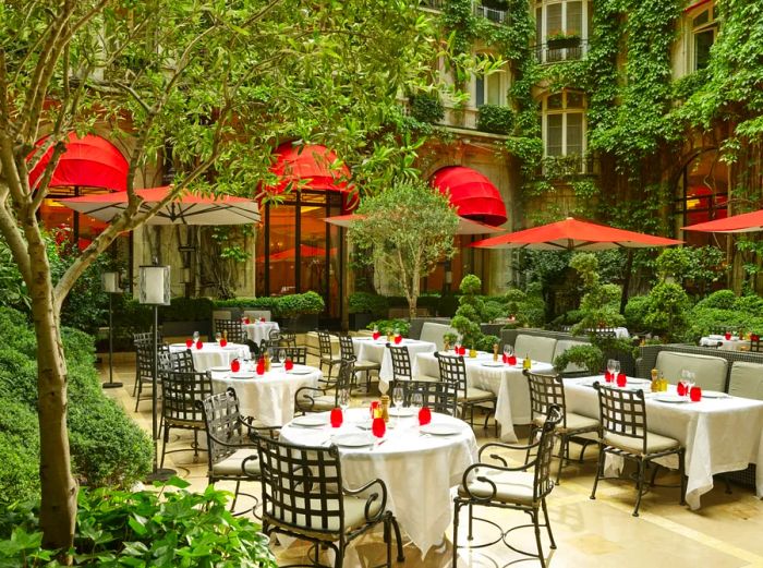 The outdoor dining tables at La Cour Jardin are enveloped in lush greenery.