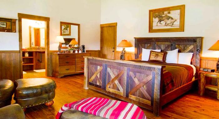 This airy guest room features warm wooden floors and a rustic wood-framed bed, adorned with a captivating painting of horses in motion.