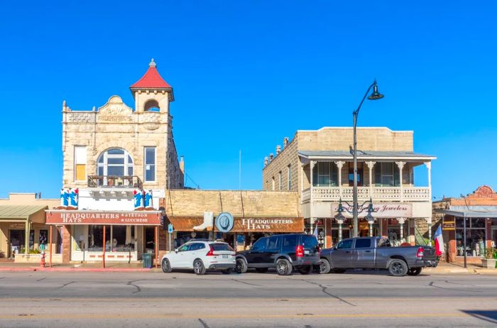 A Wild West Main Street with a few cars parked at angles in front of the shops