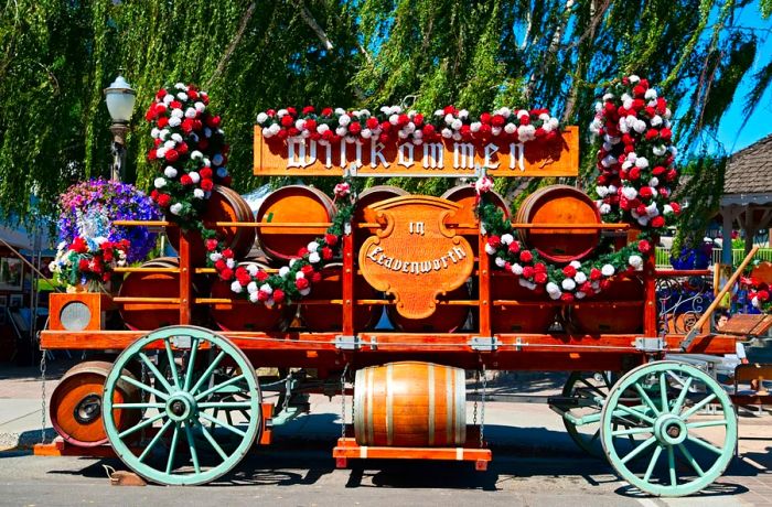 A side view of a vintage wagon adorned with barrels of beer and decorated with red and white flowers.