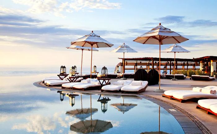 An infinity pool surrounded by umbrella-shaded white chaise lounges at Las Ventanas al Paraíso.