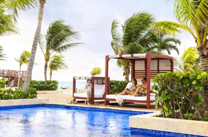 The pool at Hyatt Ziva Cancun features two cabanas, including one designed for kids, all surrounded by palm trees.