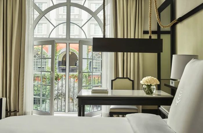 A bright guest room at the Four Seasons Hotel Mexico City features a marble-topped desk and glass doors that open to a balcony.