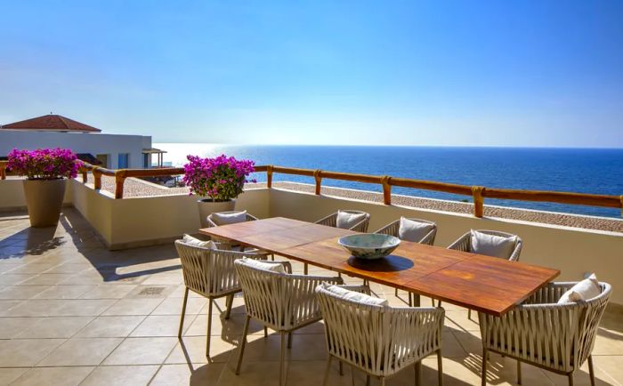 A spacious balcony of a Family Residence Suite at Grand Velas Riviera Nayarit features a dining table with eight chairs overlooking the ocean.