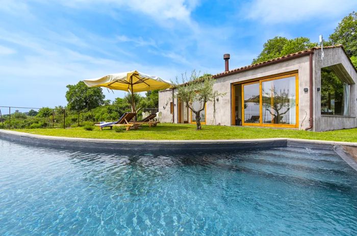 This villa at Monaci delle Terre Nere features a large pool surrounded by lounge chairs.