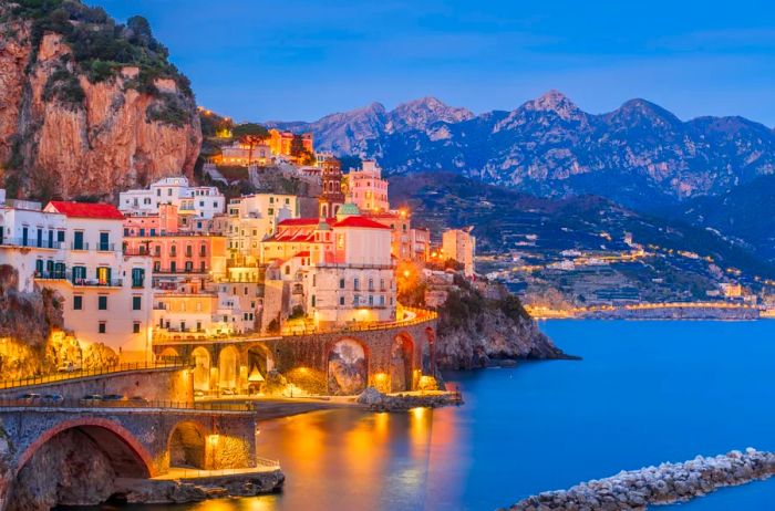 Pastel-colored buildings perched on a rocky cliffside by the water.