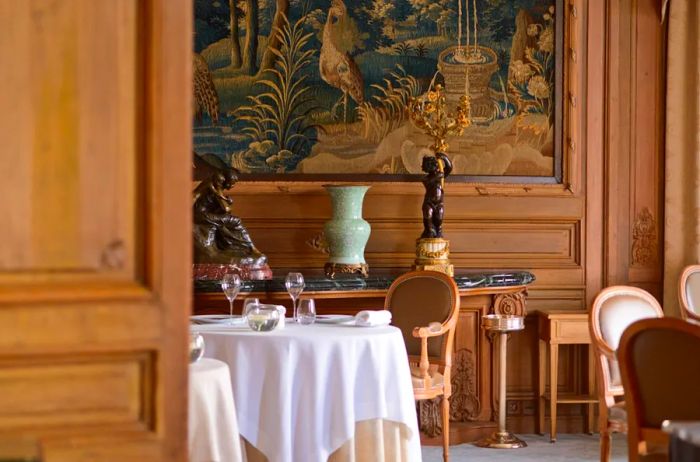 The restaurant Le Parc at Domaine Les Crayeres features elegant wooden walls and tables adorned with white tablecloths.