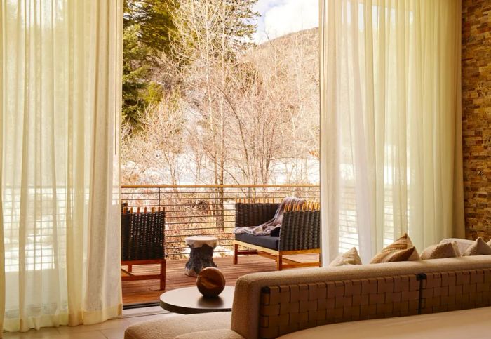 Floor-to-ceiling windows that open to a deck overlooking the trees at a Creek House.