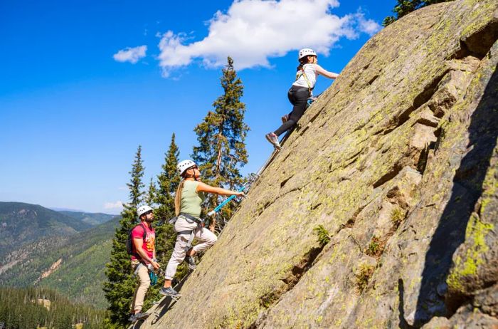 A trio of adventurers tackling a Via Ferrata at Taos Ski Valley, a unique hiking experience that includes rappelling.