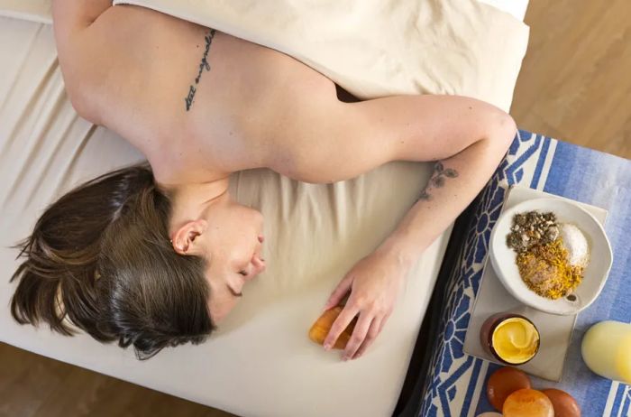 An aerial view of a woman with a back tattoo relaxing on a massage table at The Blake Hotel