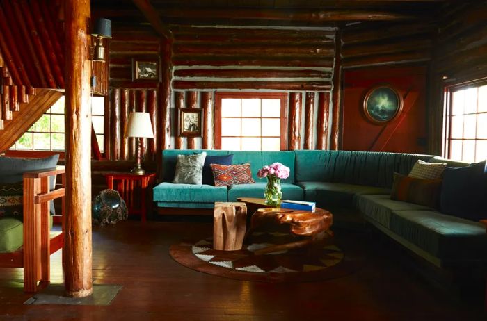 The common area of Captain Whidbey Inn features a cozy log cabin design with green couches, creating a warm and inviting atmosphere.