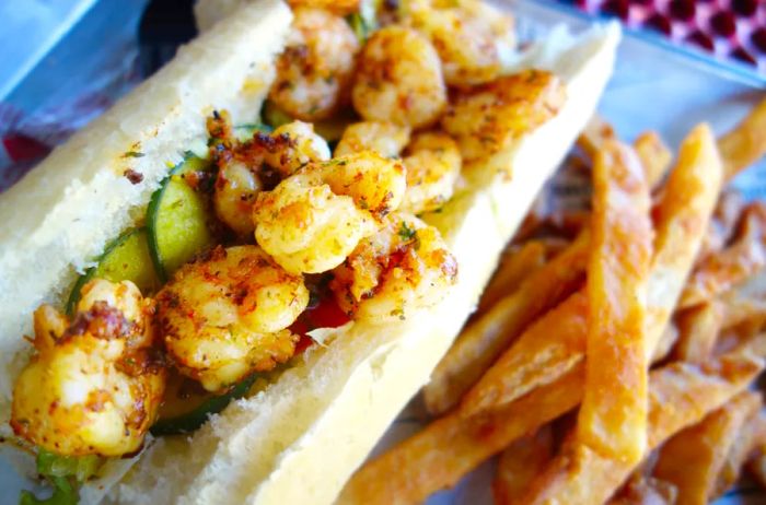 A Po Boy sandwich filled with shrimp, lettuce, and pickles on freshly baked bread.